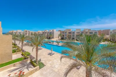 an aerial view of a resort with a swimming pool and palm trees at Coastal Vibe 2BR Mangroovy Gouna with Rooftop Cinema, BBQ, Pool & Beach Access in Hurghada