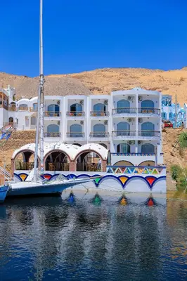 a large white building in the water next to a building at Kaya Nubian House in Aswan