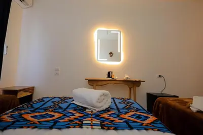 a room with a bed with a chair and a mirror at Kaya Nubian House in Aswan