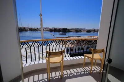 a balcony with two chairs and a view of the river at Kaya Nubian House in Aswan