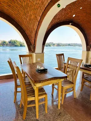 a wooden table and chairs with a view of the water at Kaya Nubian House in Aswan