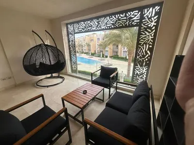 a living room with a view of a pool through a window at Pool & Sea View 2BR in Mangroovy in Hurghada