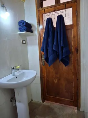 a bathroom with a sink and blue towels on a door at Ezba Guest House in Luxor