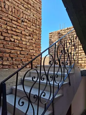a staircase with a wrought iron railing next to a brick wall at Ezba Guest House in Luxor