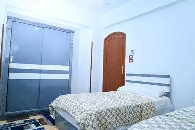a bedroom with two beds and a sliding glass door at Habiba Apartment in Luxor