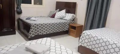 a bedroom with two beds and a table and a bedskirts at Nile palace in Jazīrat Aswān