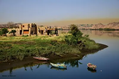 two boats are sitting on the shore of a river at Shalal Farm and guest house in Aswan