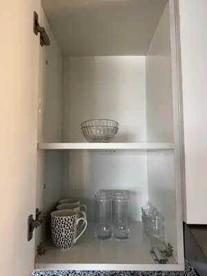 a cupboard with glasses and a bowl on a shelf at Seaside Serenity Apartment in Hurghada