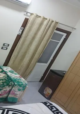 a bedroom with a bed and a door with a curtain at Gannet Alyousef City Center in Naj‘ al Maḩaţţah