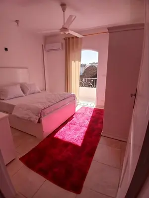 a bedroom with a bed and a red rug at Nopian 1 in Luxor