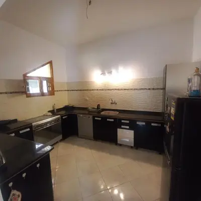 a large kitchen with black counters and a refrigerator at El Fayrouz Villa in Luxor