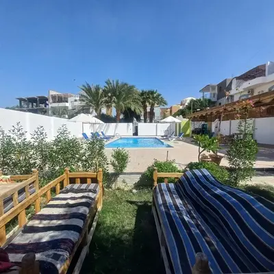 a couple of beds in front of a swimming pool at El Fayrouz Villa in Luxor