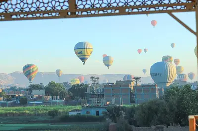a group of hot air balloons flying over a city at Holiday Dream Of Luxor in Luxor