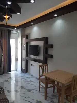 a dining room with a table and a tv on a wall at شقه سوبر لوكس in Hurghada