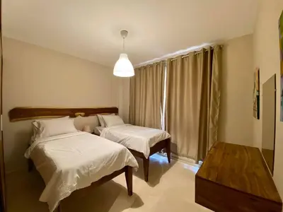 a bedroom with two beds and a table and a window at 2BR Mangroovy Ground floor in Hurghada