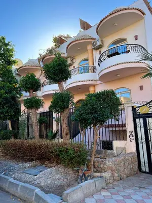 a building with a fence and trees in front of it at Sunrise Apartment in Hurghada