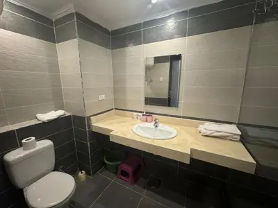 a bathroom with a sink and a toilet and a mirror at Cozy one bedroom in a compound with beach ac in Hurghada