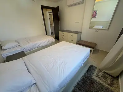 a bedroom with two beds and a mirror and a dresser at Cozy one bedroom in a compound with beach ac in Hurghada