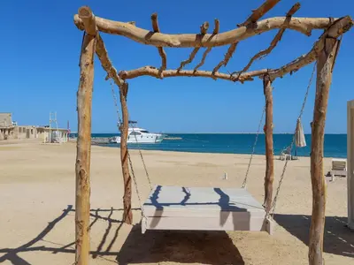 a swing on a beach with the ocean in the background at Cozy Studio 1st Avenue South Side in Hurghada
