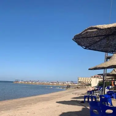 a beach with chairs and umbrellas and the ocean at Hurghada mit Charme in Hurghada