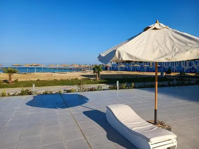 a white chair under an umbrella next to a pool at Vitamin Sea, Beach Front Central Free Wi-Fi in Hurghada