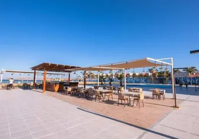 a patio with tables and chairs next to a pool at Vitamin Sea, Beach Front Central Free Wi-Fi in Hurghada