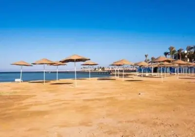 a group of umbrellas on a beach with the ocean at Vitamin Sea, Beach Front Central Free Wi-Fi in Hurghada