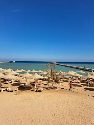 a beach with a bunch of umbrellas and the ocean at Studio in elkarma resort & aqua park in Hurghada