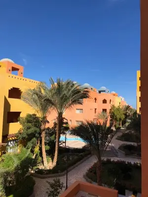 a view of a resort with palm trees and a building at Home from Home Al Dora Residence in Hurghada