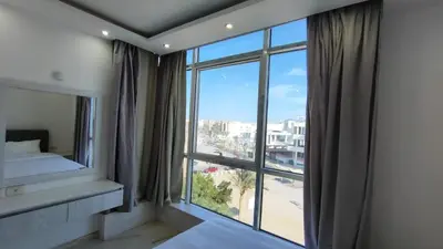 a bedroom with a large window with a view of a city at Stylish Sunny Central 1BR Apartment Hurghada in Hurghada