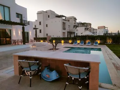 a backyard with a pool and a bar with chairs at Stay at elgouna with private heated pool villa in Hurghada