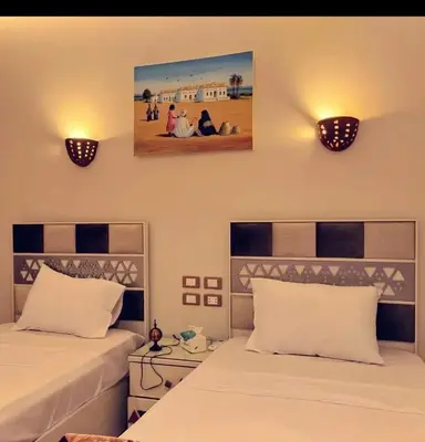 a bedroom with two beds and two lights on the wall at City centre Nile Breeze Aswan in Aswan