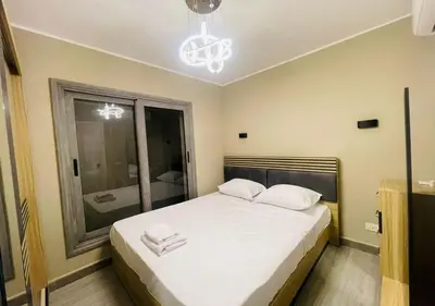 a bedroom with a bed with white sheets and a chandelier at Apartment 3 Bedrooms Bali BR C1-D with Private Pool at Bali in Hurghada