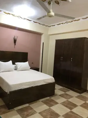 a bedroom with a large bed and a brown cabinet at Habu Garden Apartment in Luxor
