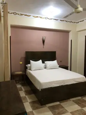 a bedroom with a large bed with white sheets and pillows at Habu Garden Apartment in Luxor