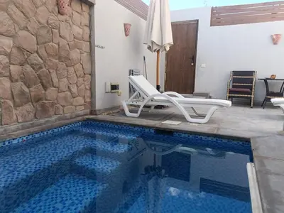 a swimming pool with a chair and an umbrella at Bali-Style 1BR 10 Min 2 Downtown in Hurghada