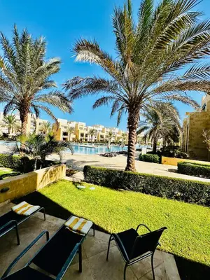 a patio with chairs and palm trees in a resort at 2 Bedrooms Ground Floor Pool view in Mangroovy Residence in Hurghada