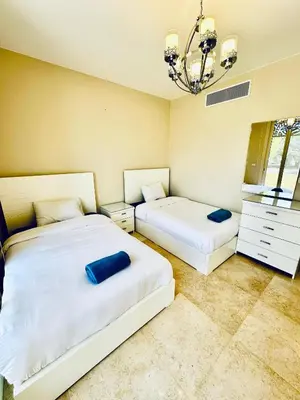 a bedroom with two beds and a chandelier at 2 Bedrooms Ground Floor Pool view in Mangroovy Residence in Hurghada