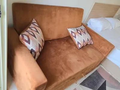 a brown couch with two pillows on a bed at Florenza Khamsin bird in Hurghada