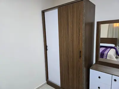 a bedroom with a mirror and a wooden cabinet at Tiba Golden Down Town in Hurghada