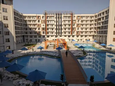 a large swimming pool with blue umbrellas in front of a building at Tiba Golden Down Town in Hurghada