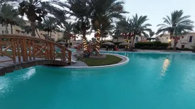 a bridge over a pool in a resort with palm trees at Palma Resort A155 Chalet Hurghada in Hurghada