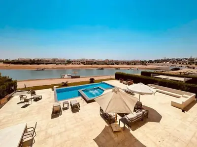 a swimming pool with umbrellas and lounge chairs and a swimming pool at Luxury villa in gouna in Hurghada