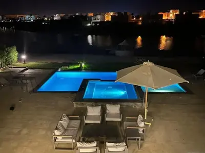 a patio with an umbrella and chairs and a pool at Luxury villa in gouna in Hurghada