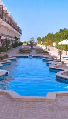 a swimming pool with blue water in front of a building at Fox Beach Inn in Hurghada