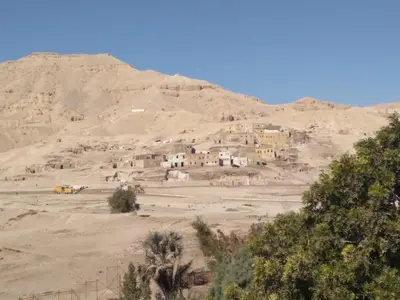 a village in the desert with a mountain in the background at Mountain hug house in Luxor