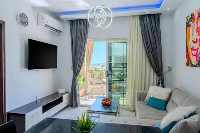 a living room with a couch and a tv at Strandapartment mit Meerblick & Pool im Juliana Beach Resort, Hurghada in Hurghada
