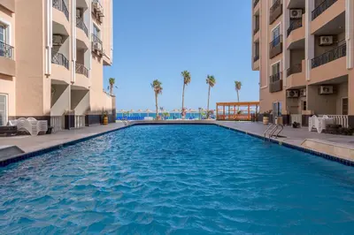 a swimming pool in the middle of two buildings at Strandapartment mit Meerblick & Pool im Juliana Beach Resort, Hurghada in Hurghada