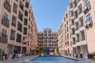 a pool with a playground in the middle of two apartment buildings at Strandapartment mit Meerblick & Pool im Juliana Beach Resort, Hurghada in Hurghada