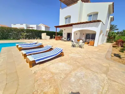a group of lounge chairs sitting next to a house at White villa in Hurghada